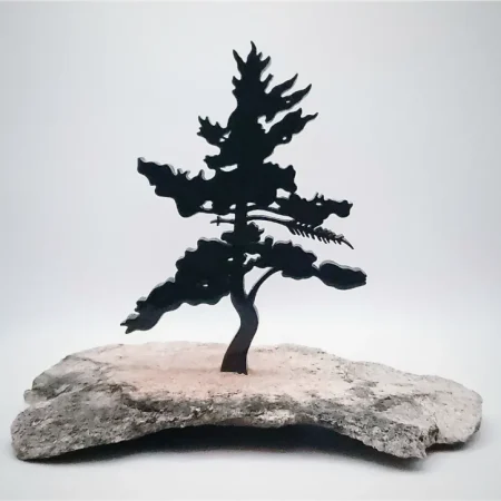 A black single pine tree silhouette is fixed onto a grey and black speckled granite base.