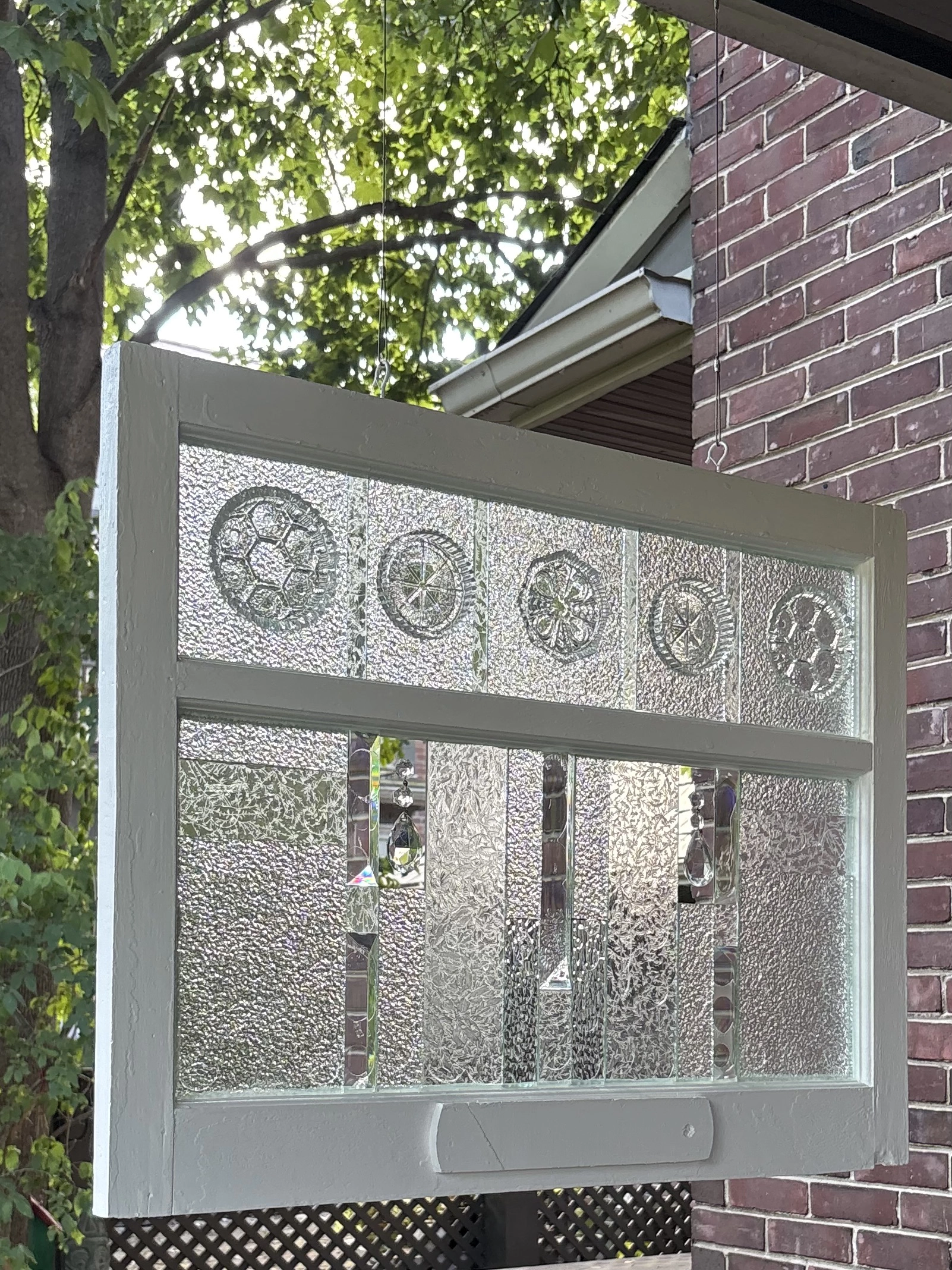 Photograph of Cathy Ogrodnik’s work of a window panel featuring textured glass with five circular stained glass designs along the top.