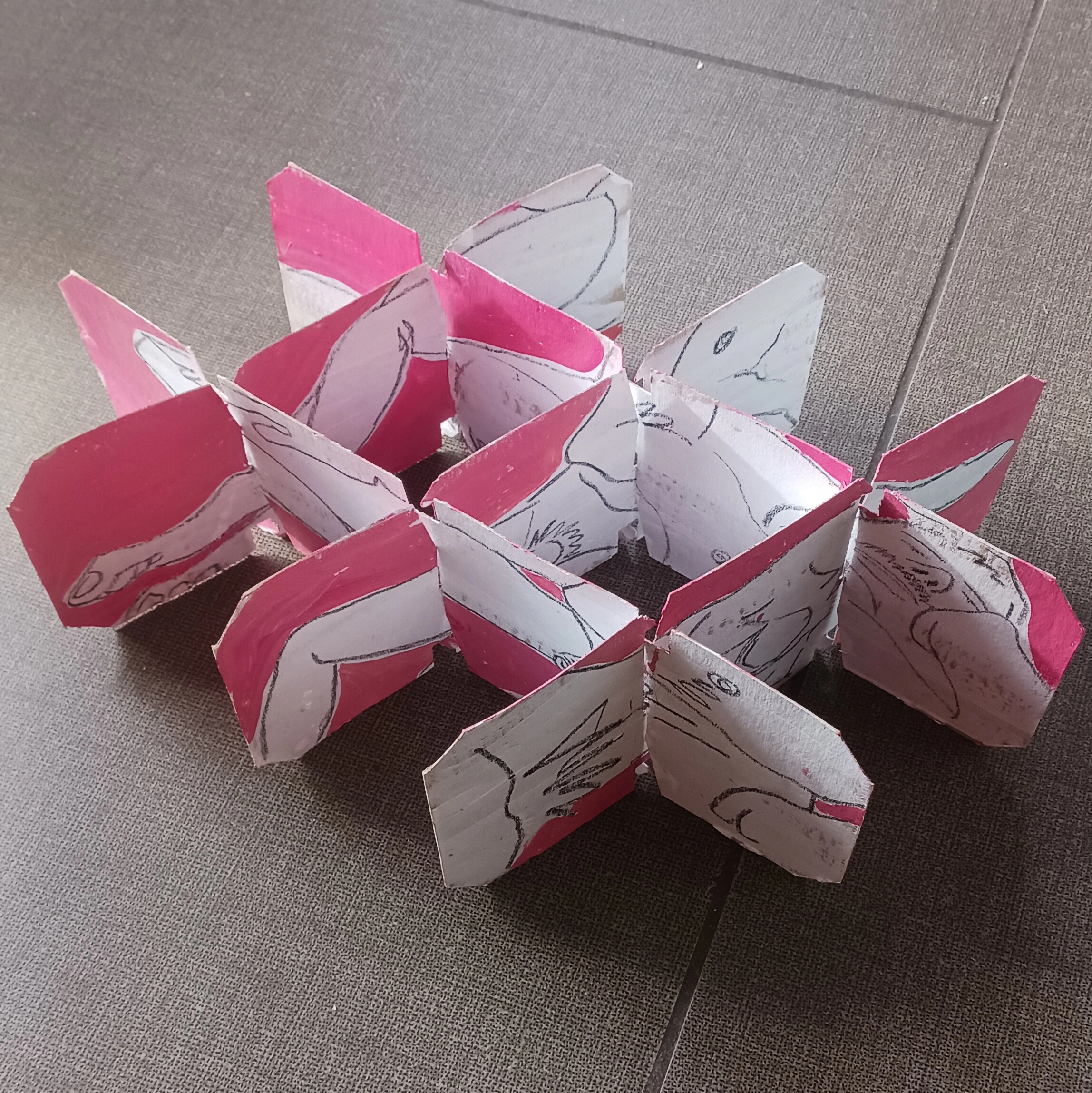 Photograph of a Jeffrey Macklin sculpture titled “boys” features a pink and white insert sculpture on kraft card.